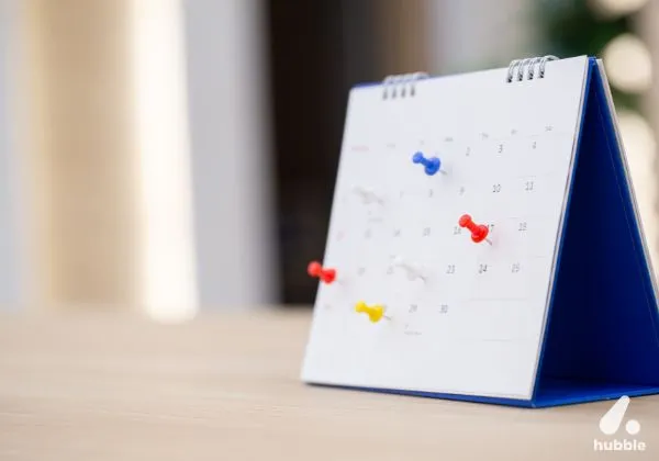 Desk calendar with coloured push pins marking key dates, representing planning impactful corporate events.