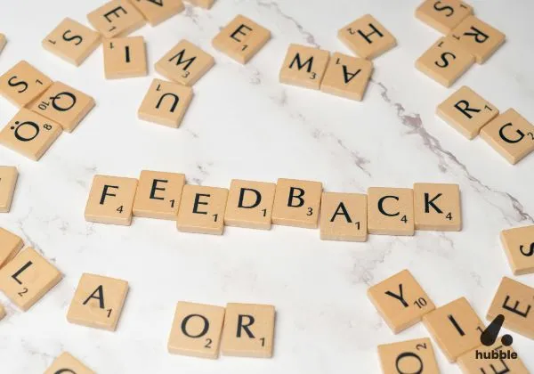 Wooden letter tiles spelling "FEEDBACK" on a marble surface.
